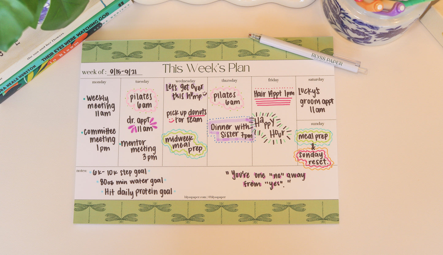 Weekly planner on a desk with a pen and decorative items