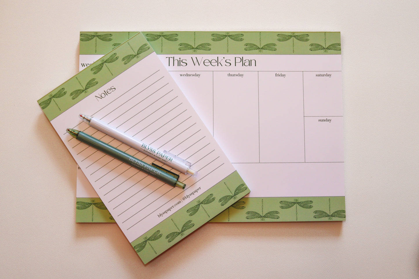 Weekly planner pad with a matching notepad and pen on a light background