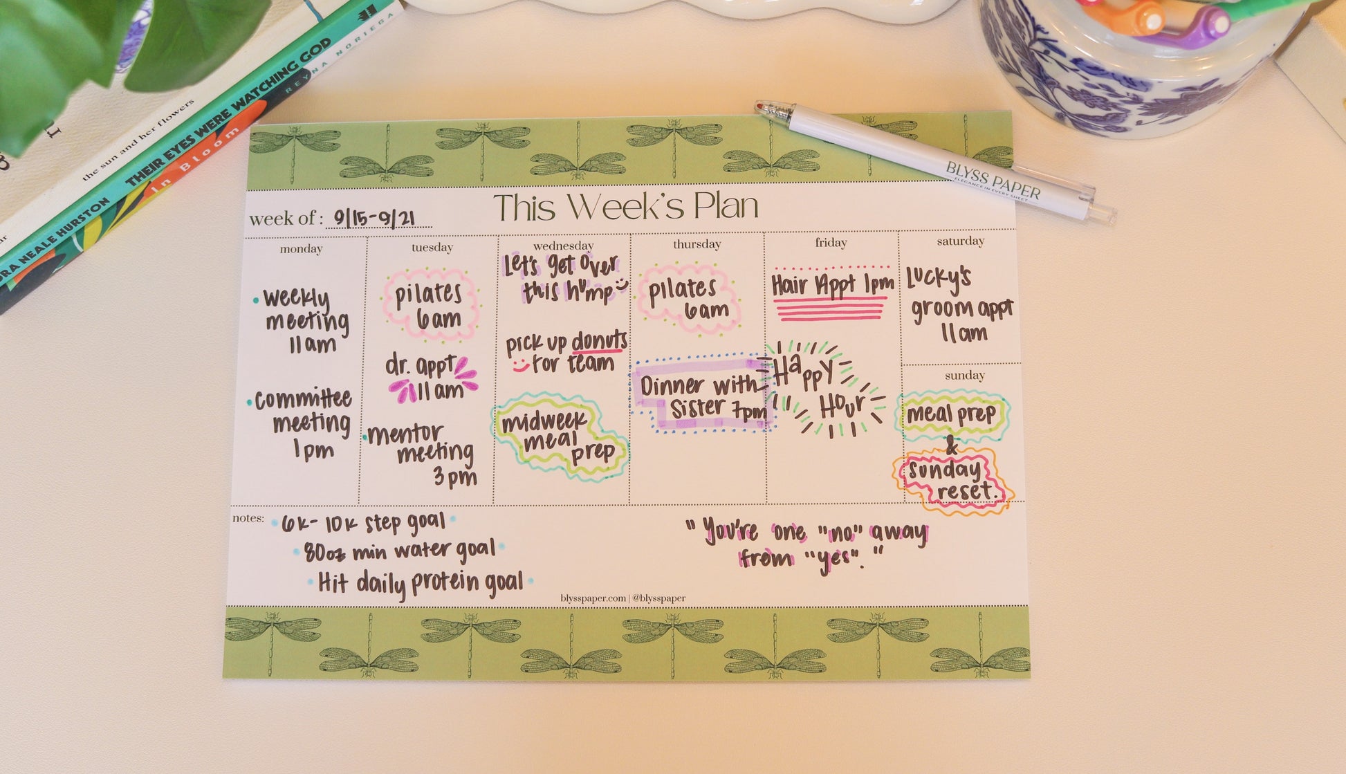 Weekly planner on a desk with a pen and decorative items