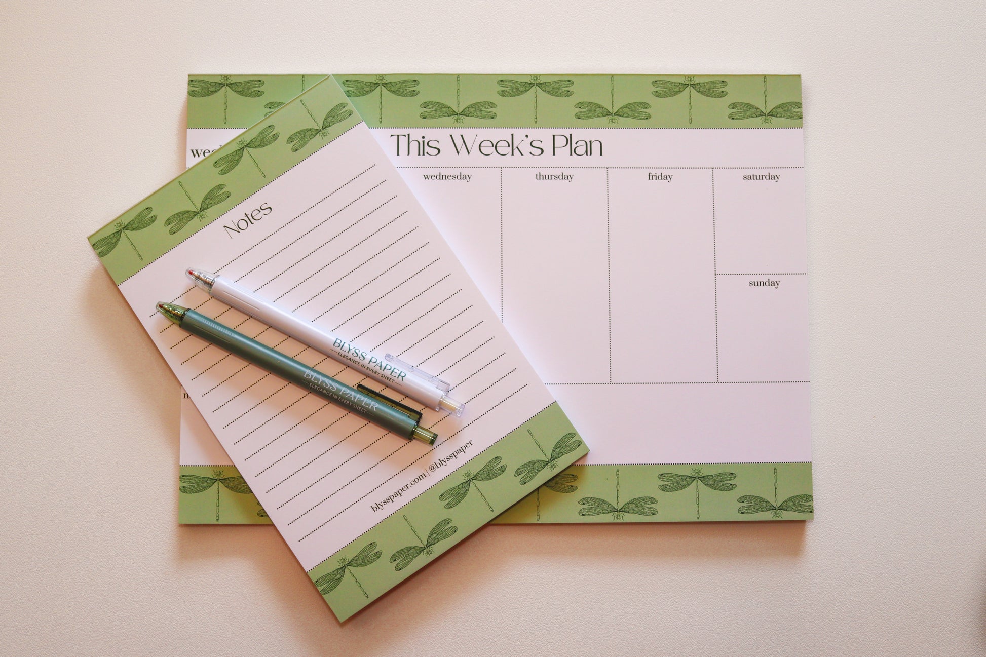 Weekly planner pad with a matching notepad and pen on a light background